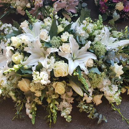 The Casket Spray Funeral Flowers by ReCreation Flowers features white lilies, roses, and lush greenery—an elegant tribute to honor your loved one with beautiful funeral flowers.