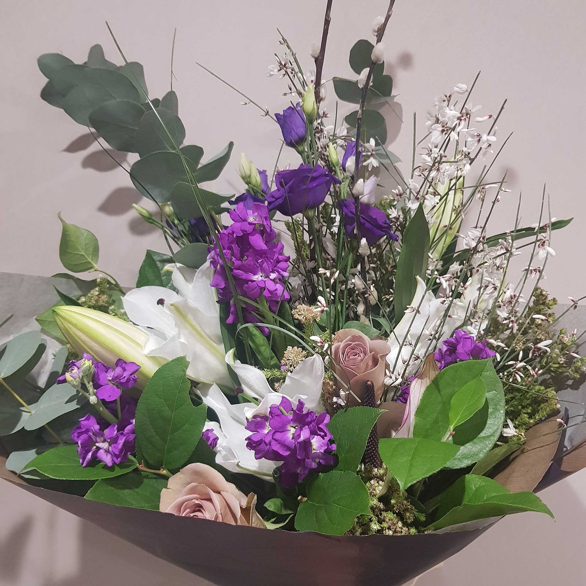 Florist Choice - Pastel by ReCreation Flowers: a beautiful mix of white lilies, purple blooms, pale pink roses, and greenery—expertly arranged with seasonal flowers in brown wrap by your Leigh on Sea florist.