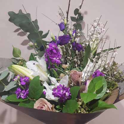 Florist Choice - Pastel by ReCreation Flowers: a beautiful mix of white lilies, purple blooms, pale pink roses, and greenery—expertly arranged with seasonal flowers in brown wrap by your Leigh on Sea florist.