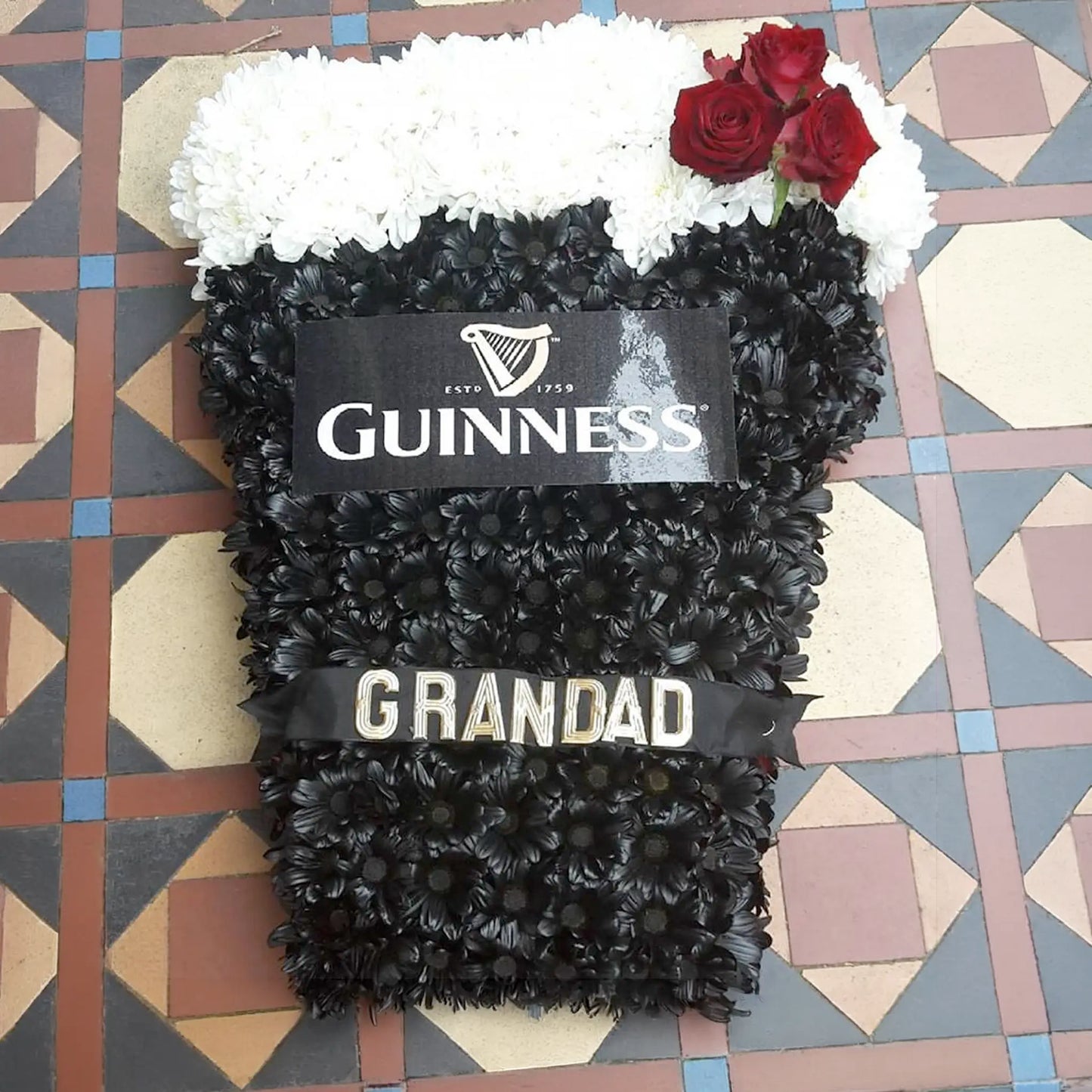 ReCreation Flowers’ Special Tributes offers a unique funeral arrangement styled as a pint of Guinness, with white flowers for foam, red roses, black blooms, a Guinness label, and a GRANDAD ribbon—an unforgettable floral tribute.